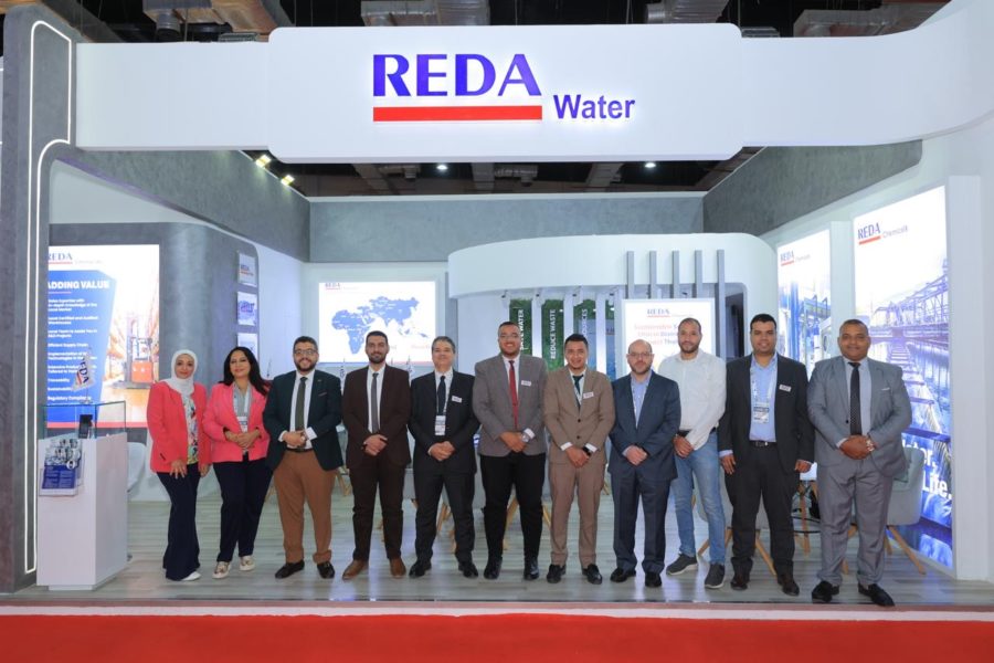 Group of professionals posing in front of the REDA Water booth at a trade show.
